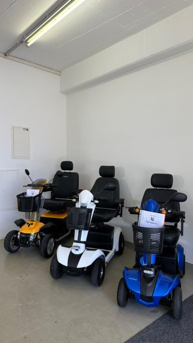 Vier Elektromobile in einem signalfarbenen Raum, bereit zur Nutzung.