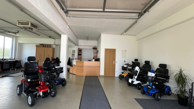 Modern Verkaufsraum mit verschiedenen Elektromobilen und Empfangstheke.